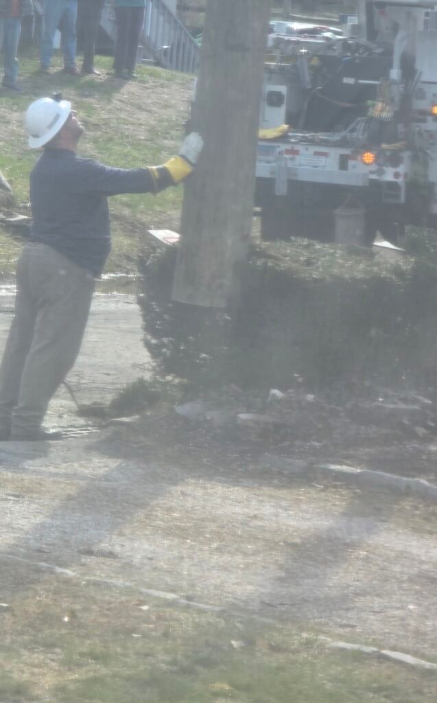 Lineman guiding a utility pole into place near a bucket truck